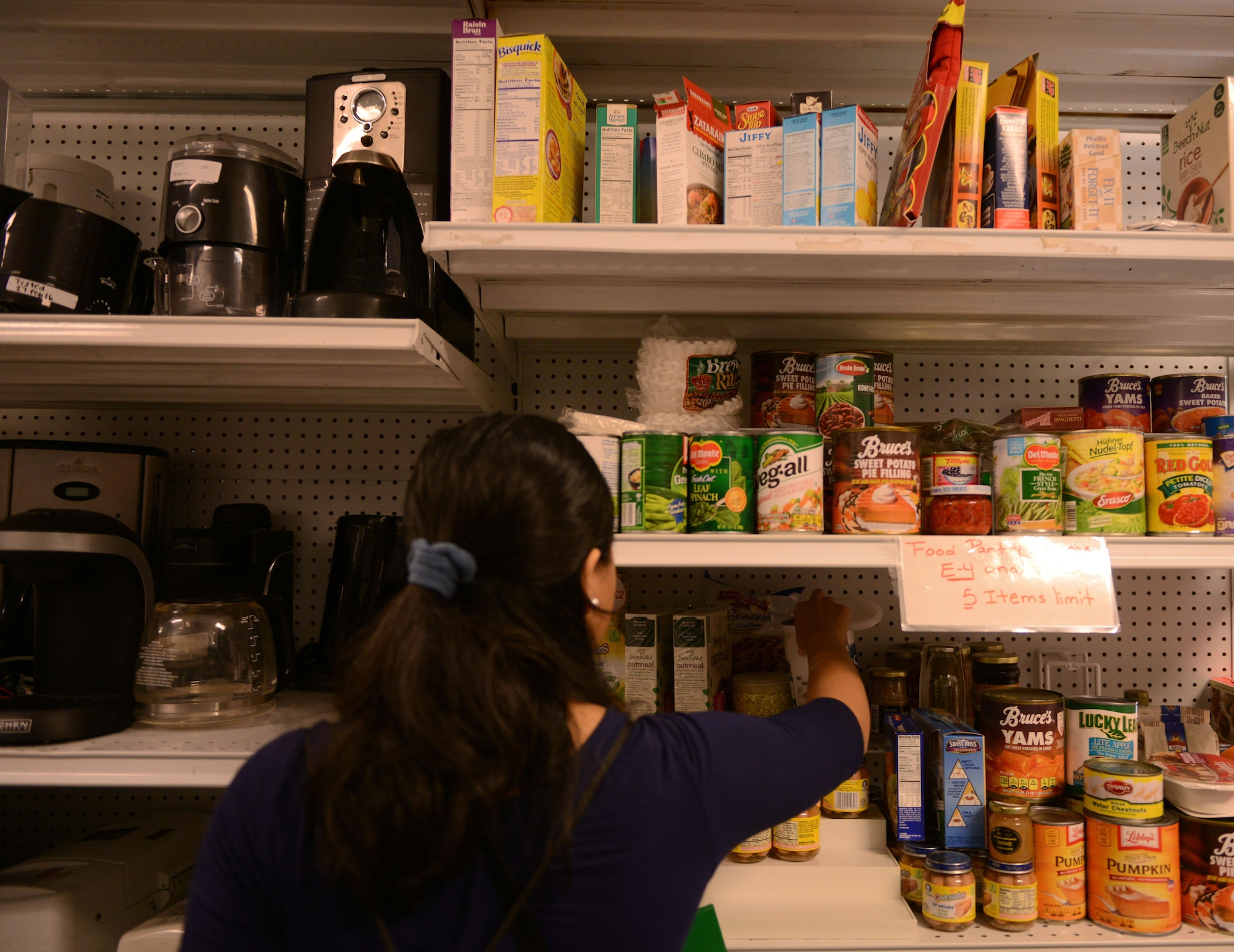 A military spouse picks canned goods being given away at the Airman’s Attic at Ramstein Air Base, Germany, June 24, 2016. The services of the Airman’s Attic are available to active-duty military personnel E-5 and below and their families. (U.S. Air Force Photo/ Airman 1st Class Joshua Magbanua)