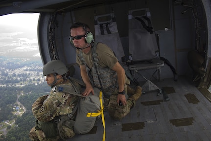 Spc. Kristen Root, 982nd Combat Camera Company, awaits the command to jump from Sgt. Christopher Emmons, U.S. Army Civil Affairs & Psychological Operations Command (Airborne), shouts commands inside a UH-60 Blackhawk during an airborne operation over St. Mere Eglise drop zone near Fort Bragg, N.C. on June 25, 2016. The USACAPOC(A), an Army Reserve unit, conducts airborne operations in order to maintain currency and proficiency. USACAPOC(A) supports the Army and Joint Force with strategic, operational, and tactical civil affairs, military information support, and information operations capabilities across the range of military operations. (U.S. Army photo by Staff Sgt. Felix Fimbres)