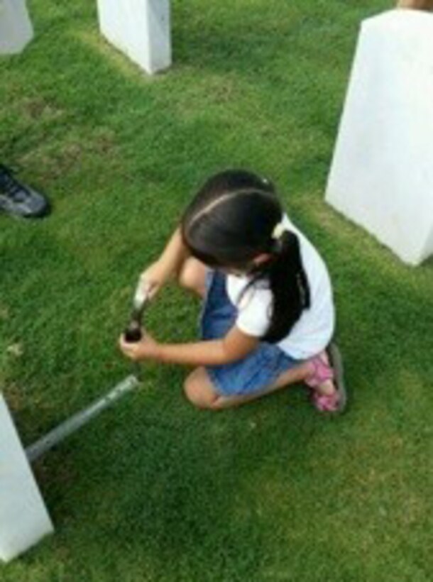 A young 482ndFW volunteer measures out the exact location to place the United States Flag on a veteran’s grave. Upon placing the flag on the grave, the adult volunteers thank the veteran for his or her service to their country.  