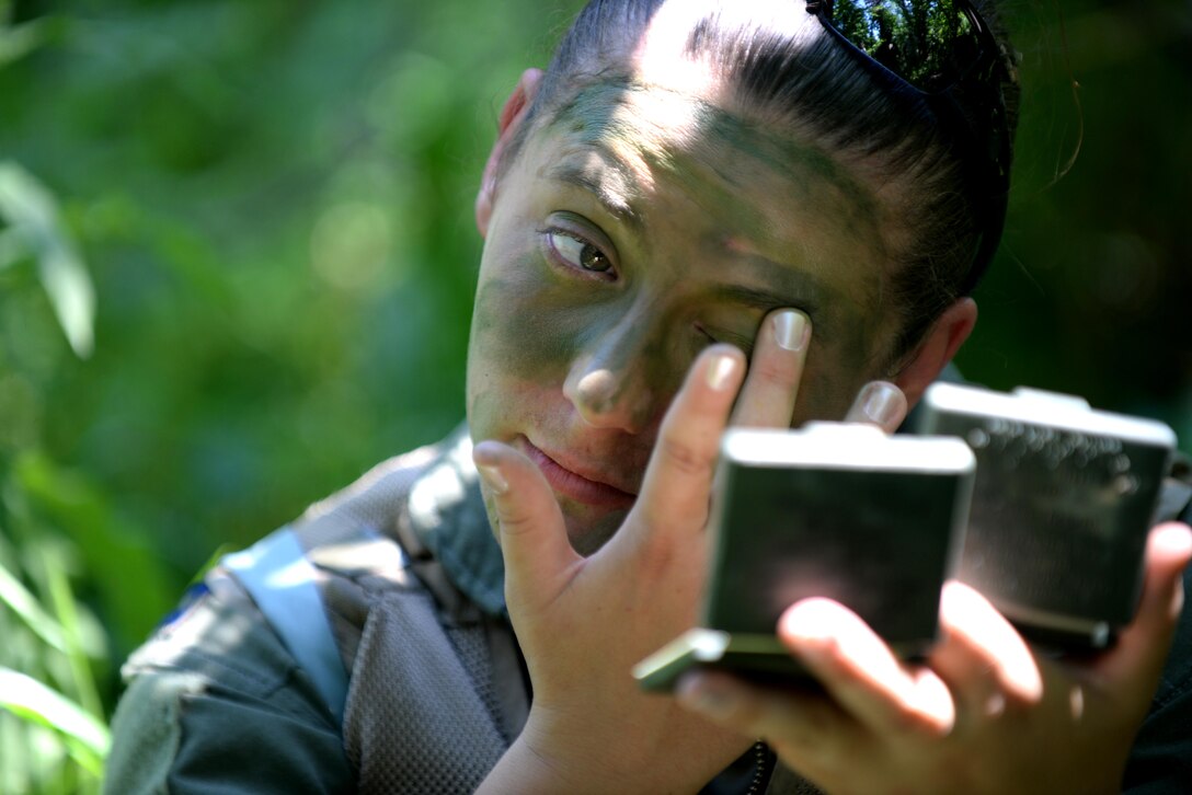 Capt. Stephanie Bradford, 37th Bomb Squadron pilot, applies camouflage face paint during Survival, Evasion, Resistance and Escape training near Fort Meade, S.D., June 21, 2016. The objective of this training is to prepare aircrew to improve their skills to survive in the wilderness, relocate to a safe area undetected, and await friendly forces to rescue them. (U.S. Air Force photo by Senior Airman Rebecca Imwalle/Released)