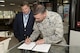 Lt. Col. Donald Tasker III, 436th Force Support Squadron commander, signs a memorandum of understanding as Ray Bivens, Delaware Division of Parks and Recreation state parks director, observes June 23, 2016, at Dover Air Force Base, Delaware. The MOU is one of many that make up First State Community Partnership. (U.S. Air Force photo/Senior Airman Aaron J. Jenne)