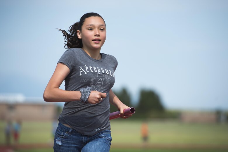 Ashley Hermasilla, Ellicott middle school student, carries a baton while running her leg of a relay race during the Schriever School Age Care Olympic Day event at Schriever Air Force Base, Colorado, Wednesday, June 22, 2106. Hermasilla was one of more than 150 Ellicott summer program youth invited to the base by the SAC to participate in the event.  (U.S. Air Force Photo/Dennis Rogers)