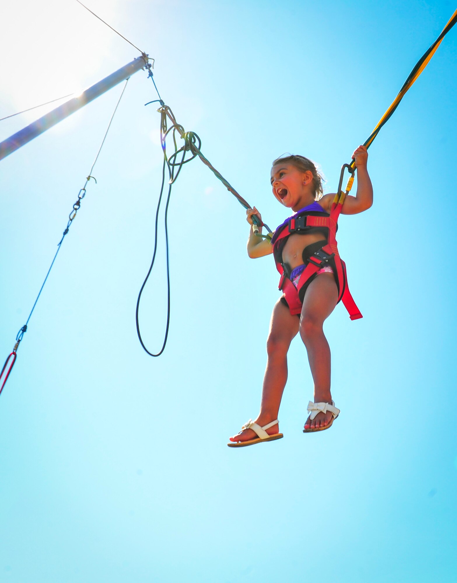 A child laughs as she enjoys a bungee trampoline attraction during the Sound of Independence at Hurlburt Field, Fla., June 24, 2016. The bungee trampoline is one of many attractions offered at the Sound of Independence. Other attractions included a zip line and inflatable water slides (U.S. Air Force photo by Airman Dennis Spain)