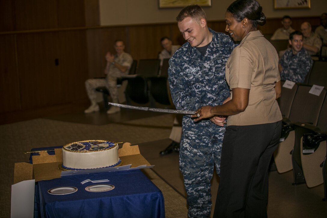 Hospital Corpsman Petty Officer 1st Class Debra Pee (right), and Hospital Corpsman Michael Wildroudt (left), the most senior and junior hospital corpsman in their unit, perform a cake cutting ceremony during the 118th Hospital Corpsman birthday celebration at Marine Corps Support Facility New Orleans, June 28, 2016. The cake cutting ceremony signifies the importance of the rich history of the Navy Hospital Corps and the legacy its members are expected to continue. 