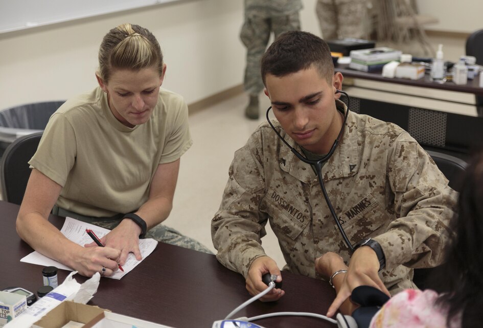 Lance Cpl. Alex A. Dossantos (right), a supply administration and operations specialist with 4th Dental Battalion, 4th Marine Logistics Group, Marine Forces Reserve, takes a patient’s blood pressure readings under the supervision of Air Force Staff Sgt. Keri L. Christian (left), a medical training manager with 190th Medical Group, 190th Air Refueling Wing, Air National Guard, at Kauai Community College during Innovative Readiness Training Tropic Care 2016, June 25, 2016. Dossantos studies biology and psychology at the University of Georgia in Athens, Ga., and hopes to pursue a career in neurology. IRT Tropic Care 2016 is part of a civil and joint military program to improve military readiness while simultaneously providing quality services to underserved communities throughout the United States. (U.S. Marine Corps photo by Sgt. Ian Leones/Released)