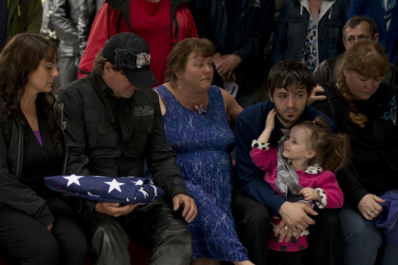Fred Becker V holds the flag offered to him at the end of the flag-folding ceremony for his father Fred "Bulldog" Becker IV's funeral June 24. Bulldog was heavily involved in the Anchorage community, and more than 1,000 Airmen and Soldiers lined the streets for his processional, consisting of hundreds of motorcyclists from around the community. (U.S. Air Force photo by Senior Airman Kyle Johnson)