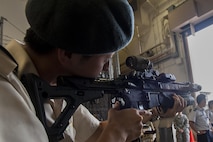 Japan Ground Self-Defense Force 1st Lt. Akifumi Saito, UH-1 pilot attending the 52nd Joint Tactical Operations Course, tries holding weapons from the 320th Special Tactics Squadron during a tour of the 353rd Special Operations Group June 21, 2016, at Kadena Air Base, Japan. Japan Air Self-Defense Force and JGSDF members use the tour of Kadena to learn about the U.S. Air Force and exchange knowledge between the two countries. (U.S. Air Force photo by Airman 1st Class Corey M. Pettis)