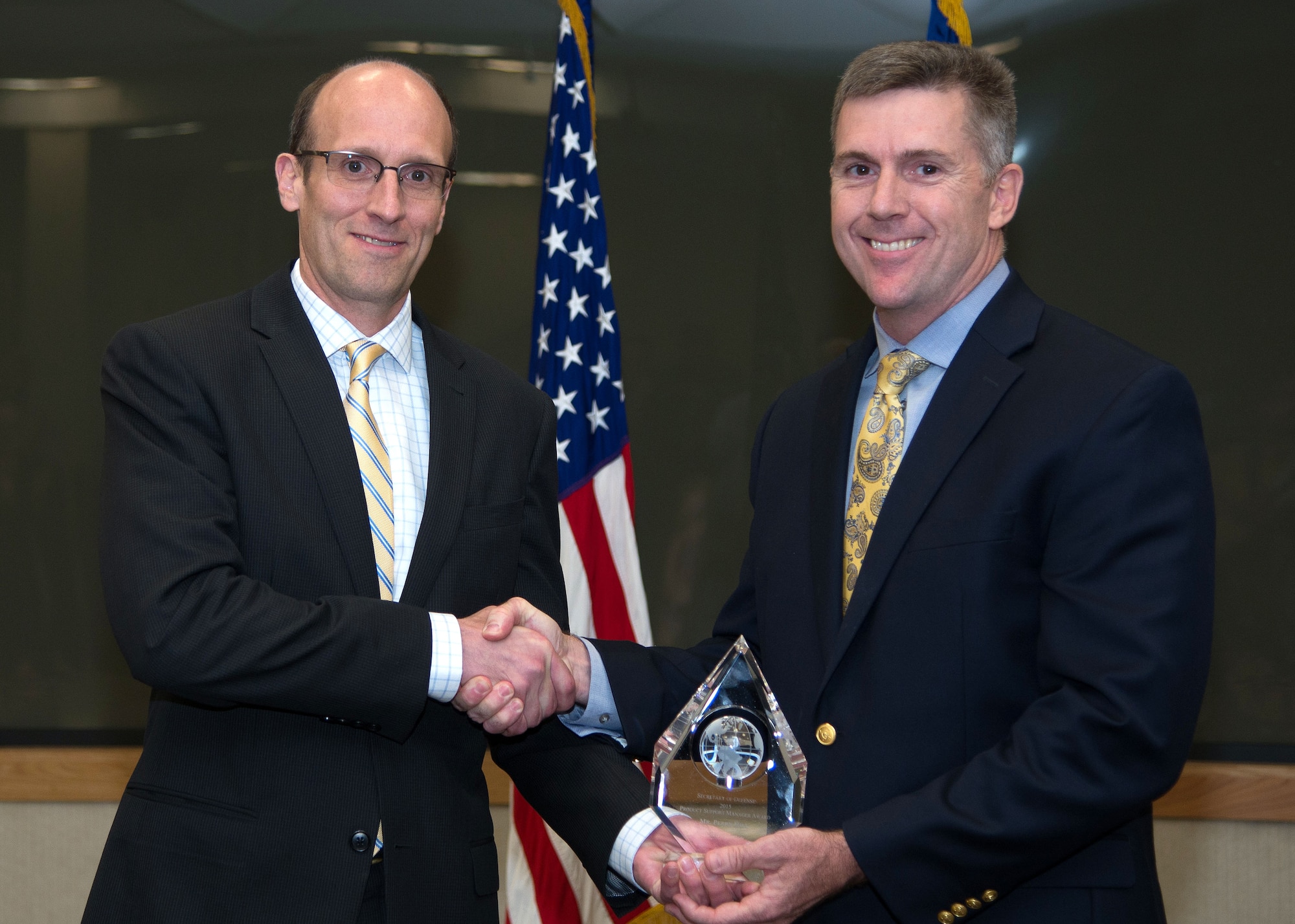 Terry Emmert, deputy assistant secretary of Defense for Materiel Readiness, presents Perry Hill, director of Logistics for the Nuclear Command, Control and Communications Integration Directorate at Hanscom Air Force Base, Mass., with the 2015 Secretary of Defense Product Support Manager Award in the category of Major Weapon System/Other Weapon System, acquisition category II or below, June 23 at the base conference center. The award recognizes PSMs as “important partners” in providing the best support for warfighters and Hill received the award for work performed in his previous position as product support manager and chief of logistics for the Command, Control, Communications, Intelligence and Networks Directorate’s Space, Aerial and Nuclear Networks Division. (U.S. Air Force photo by Mark Herlihy)