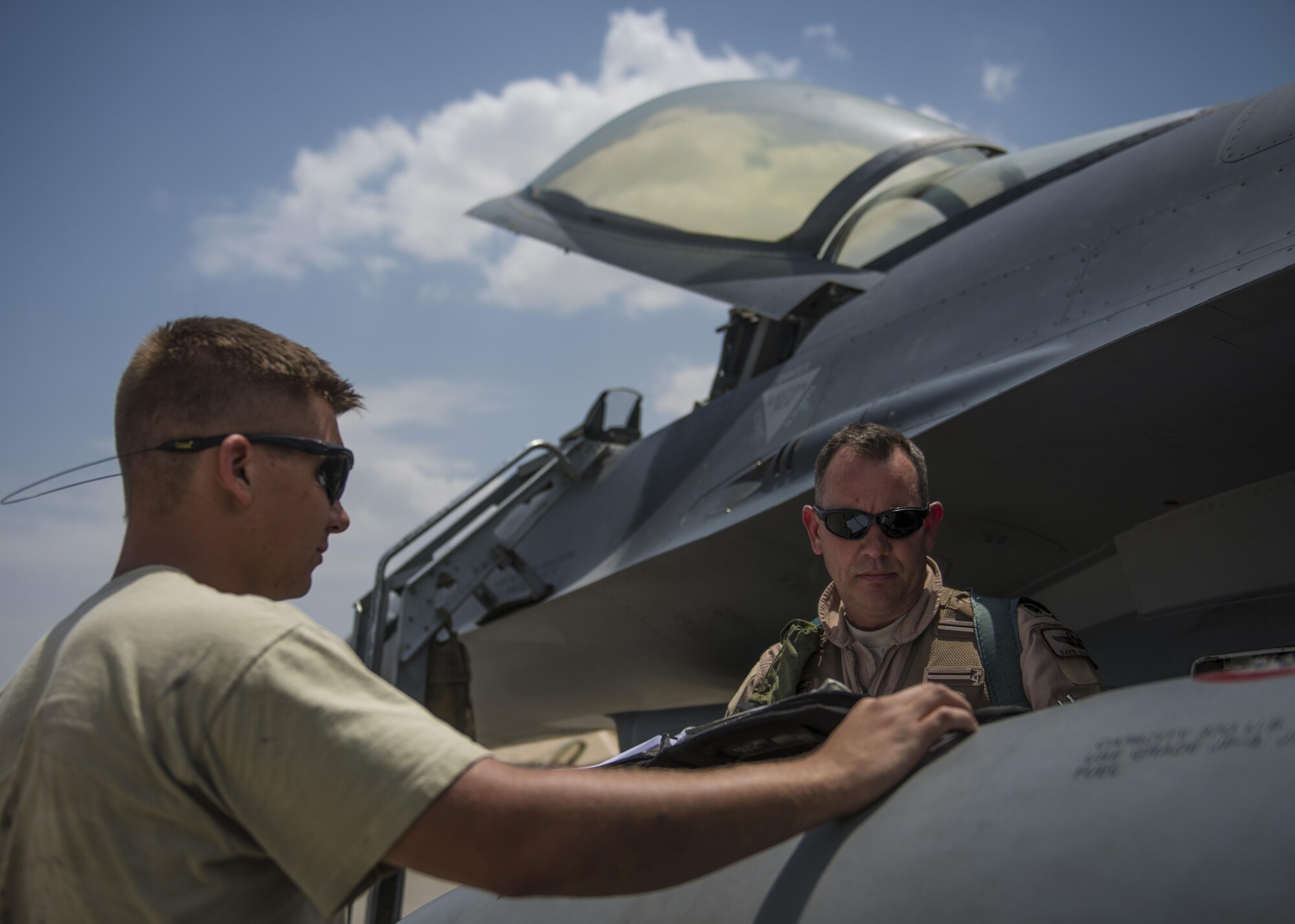 Lt. Col. David Efferson (right), 457th Expeditionary Fighter Squadron commander, and Senior Airman Brandon Hellin (left), 455th Expeditionary Maintenance Squadron crew chief, review an F-16C Fighting Falcon flight checklist, June 28, 2016, Bagram Airfield, Afghanistan. The F-16C is a compact, multi-role fighter aircraft that is highly maneuverable in air-to-air combat and air-to-surface attacks. (U.S. Air Force photo by Senior Airman Justyn M. Freeman)