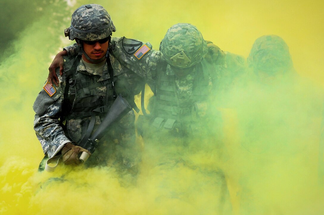 Army Pfc. Tim Hofmann, left, and Spc. Alex Sidoa, right, help Sgt. Michael Barnes through the smoke marking a simulated casualty extraction point during the Ready Warrior Competition at Camp Madbull at Joint Base Elmendorf-Richardson, Alaska, June 23, 2016. Air Force photo by Justin Connaher