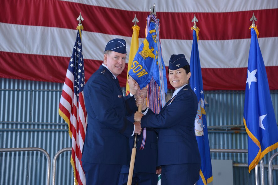 Maj. Gen. James Hecker, 19th Air Force commander, hands the 58th Special Operations Wing guidon to Col. Brenda Cartier at a change of command ceremony June 27. Cartier is the new commander of the wing. (Photo by Dennis Carlson)
