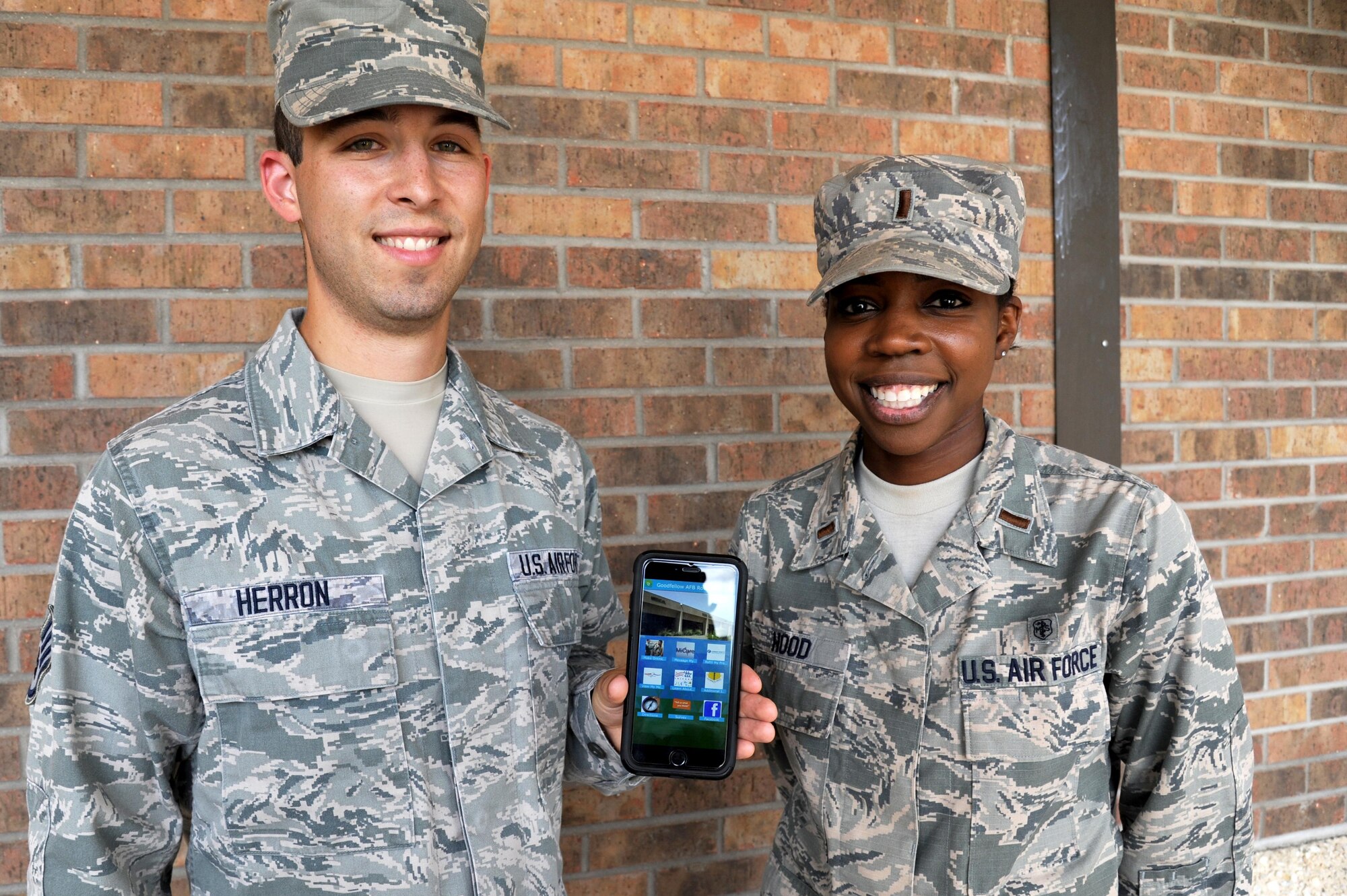 U.S. Air Force Staff Sgt. Charles Herron, 17th Medical Support Squadron command support staff NCO in charge, and 2nd Lt. Mara Hood, 17th MDSS group practice manager, pose for a photo with the new 17th Medical Group app outside the Ross Clinic on Goodfellow Air Force Base, Texas, June 24, 2016. The app is set to release in July on a variety of platforms and assist individuals with their healthcare information needs.