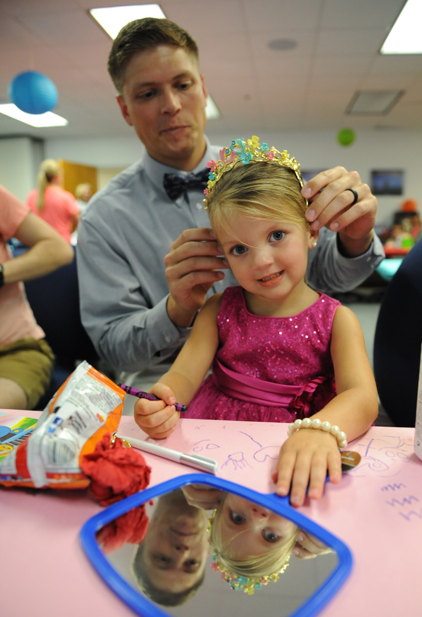 Second Lt. David Giannotti, 81st Logistics Readiness Squadron distribution officer in charge, places a tiara on his daughter, Paisley during a Daddy/Daughter Dinner and a “Do” event at the Sablich Center June 24, 2016 on Keesler Air Force Base, Miss. The event included dinner and hands-on hair styling techniques for the dads, which provided a valuable opportunity for sharing, learning new practical skills and deepening the bond between the dads and their daughters. (U.S. Air Force photo by Kemberly Groue/Released)