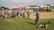 Military Working Dog Cyndy awaits command from her handler as he explains his job to Minot AFB children and families during a demonstration for Heroes in Training at Minot Air Force Base, N.D., June 24, 2016. A K-9 demonstration was one of many events put on for Minot youth to showcase different first responding units. (U.S. Air Force photo/Airman 1st Class Christian Sullivan)
