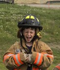 A Minot youth screams with excitement as he is about to use a fireman’s hose during Heroes in Training at Minot Air Force Base, N.D., June 24, 2016. Heroes in training showcased displays from the fire department, security forces, medical group and other first responding base agencies. (U.S. Air Force photo/Airman 1st Class Christian Sullivan)