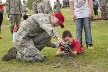 A security forces Airman shows a Minot child how to hold and aim an unloaded gun during Heroes in Training at Minot Air Force Base, N.D., June 24, 2016. Heroes in Training showcased displays from the fire department, security forces, medical group and other first responding base agencies. (U.S. Air Force photo/Airman 1st Class Christian Sullivan)
