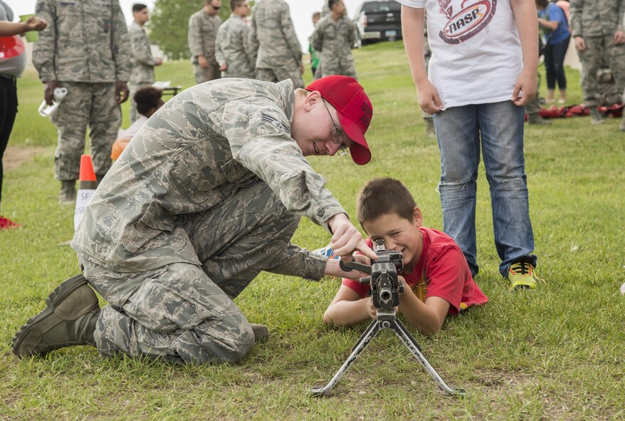 A security forces Airman shows a Minot child how to hold and aim an unloaded gun during Heroes in Training at Minot Air Force Base, N.D., June 24, 2016. Heroes in Training showcased displays from the fire department, security forces, medical group and other first responding base agencies. (U.S. Air Force photo/Airman 1st Class Christian Sullivan)