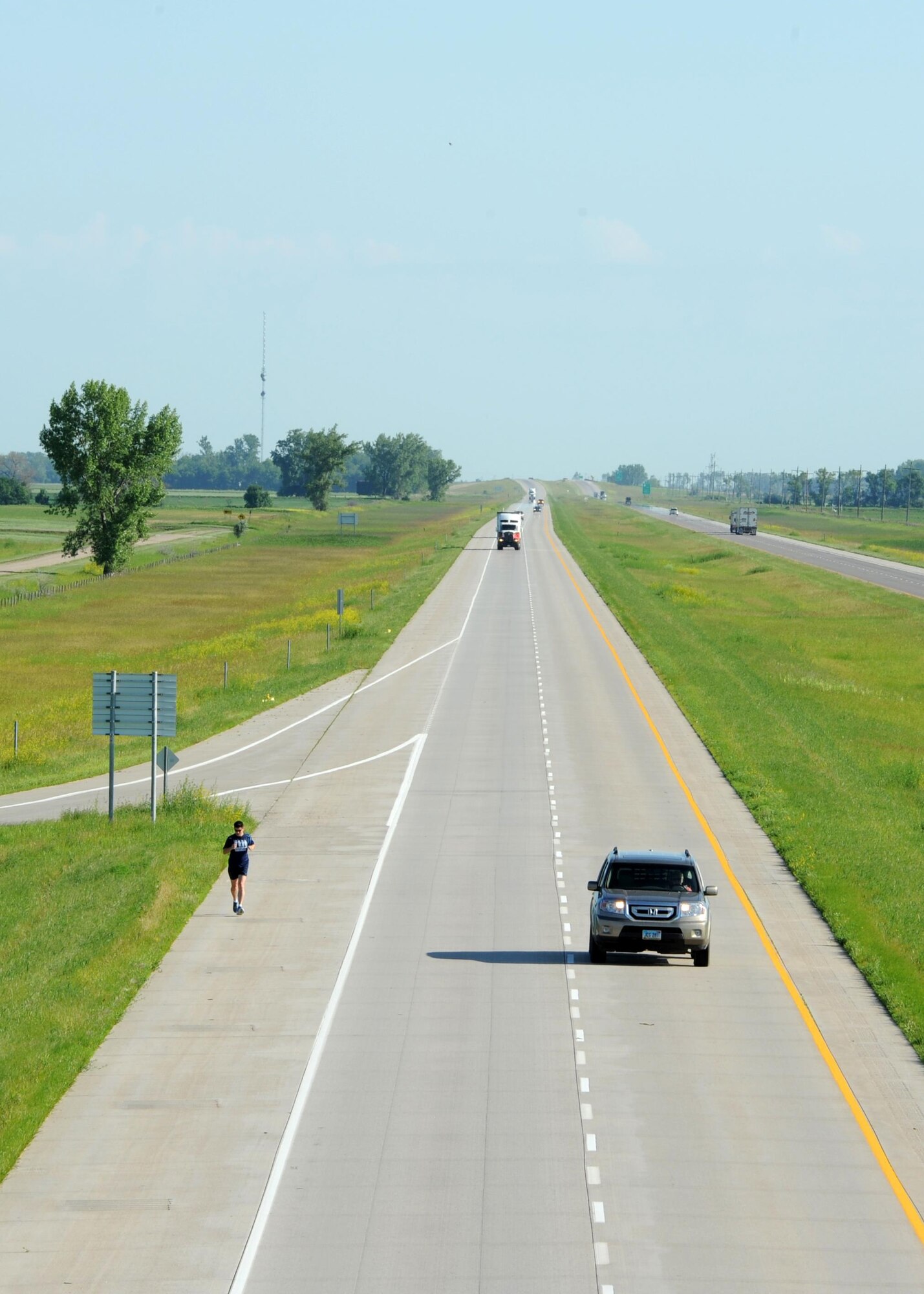 A car passes Staff Sgt. Brendan Brustad, 319th Air Base Wing assistant to the wing executive officer, as he runs along the interstate June 29, 2016, in Grand Forks, N.D. Brustad coordinated with the North Dakota Department of Transportation to run along the interstate from Winnipeg, Canada to Grand Forks Air Force Base, N.D. (U.S. Air Force photo by Senior Airman Ryan Sparks/Released)