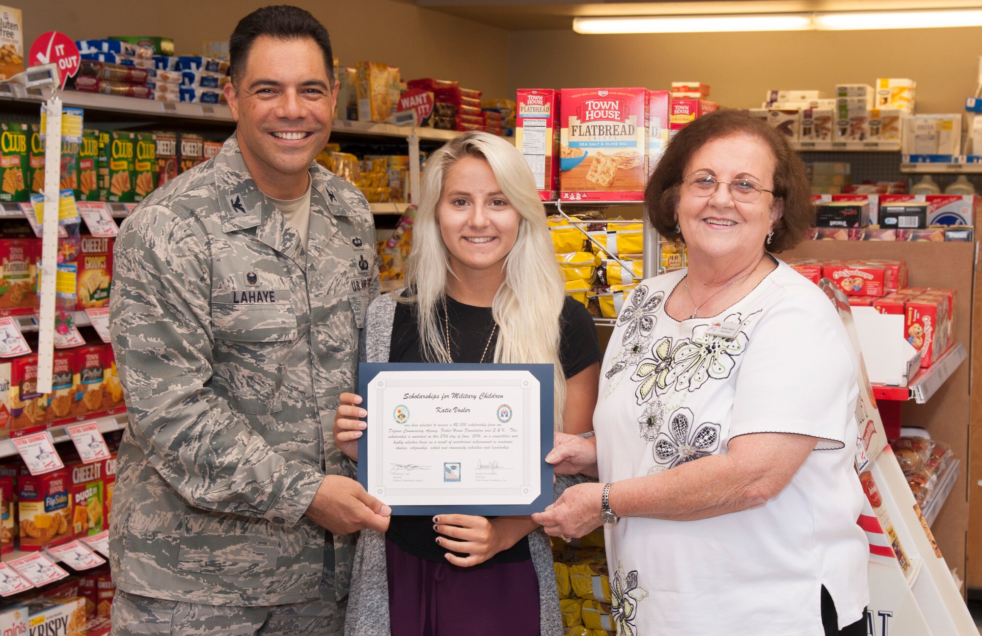 Katie Vosler, center, accepts a $2,000 college scholarship from Col. Dwayne LaHaye, left, the 71st Mission Support Group commander, and Sheila Gilbert, the director of the Vance Air Force Base Commissary, during a brief ceremony at the Commissary June 28. (U.S. Air Force photo by Tech. Sgt. James Bolinger)