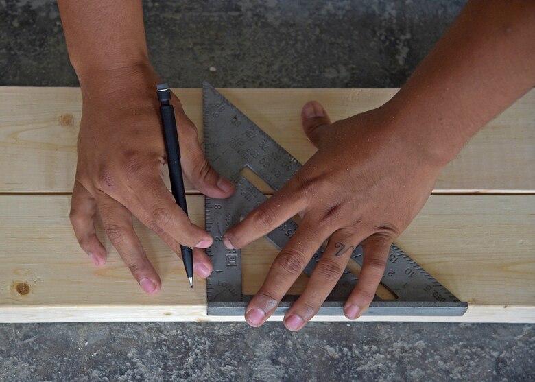 U.S. Air Force Senior Airman Eric Garcia, a structural journeyman with the 35th Civil Engineer Squadron, uses a speed square to accurately cut blocks of wood at Misawa Air Base, Japan, June 24, 2016. Structures Airmen are expected to maintain base infrastructure from the foundation up, which includes installing dry wall, painting, pouring concrete and constructing and repairing base buildings. (U.S. Air Force photo by Senior Airman Deana Heitzman)