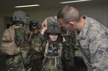 Senior Airman Thorton Willis, 374th Operations Support Squadron aircrew flight equipment journeyman, helps a Civil Air Patrol cadet don a helmet during the CAP summer encampment at Yokota Air Base, Japan, June 23, 2016. The cadets visited various sections such as the 374th Maintenance Squadron propulsion flight, 374th Operations Support Squadron aircrew flight equipment, 374th Security Forces Squadron combat arms training and maintenance, and the 730th Air Mobility Squadron (U.S. Air Force photo by Senior Airman David Owsianka/Released)