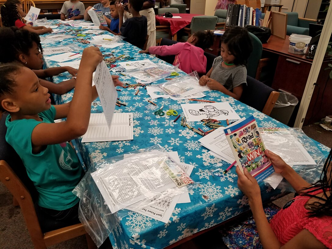 School age children look through activity packets at the “Read for the Win” summer reading program at Fort Eustis, Va, June 27, 2016. The program assists parents and guardians in promoting and maintaining crucial reading and listening skills. (U.S. Air Force photo by Beverly Joyner)