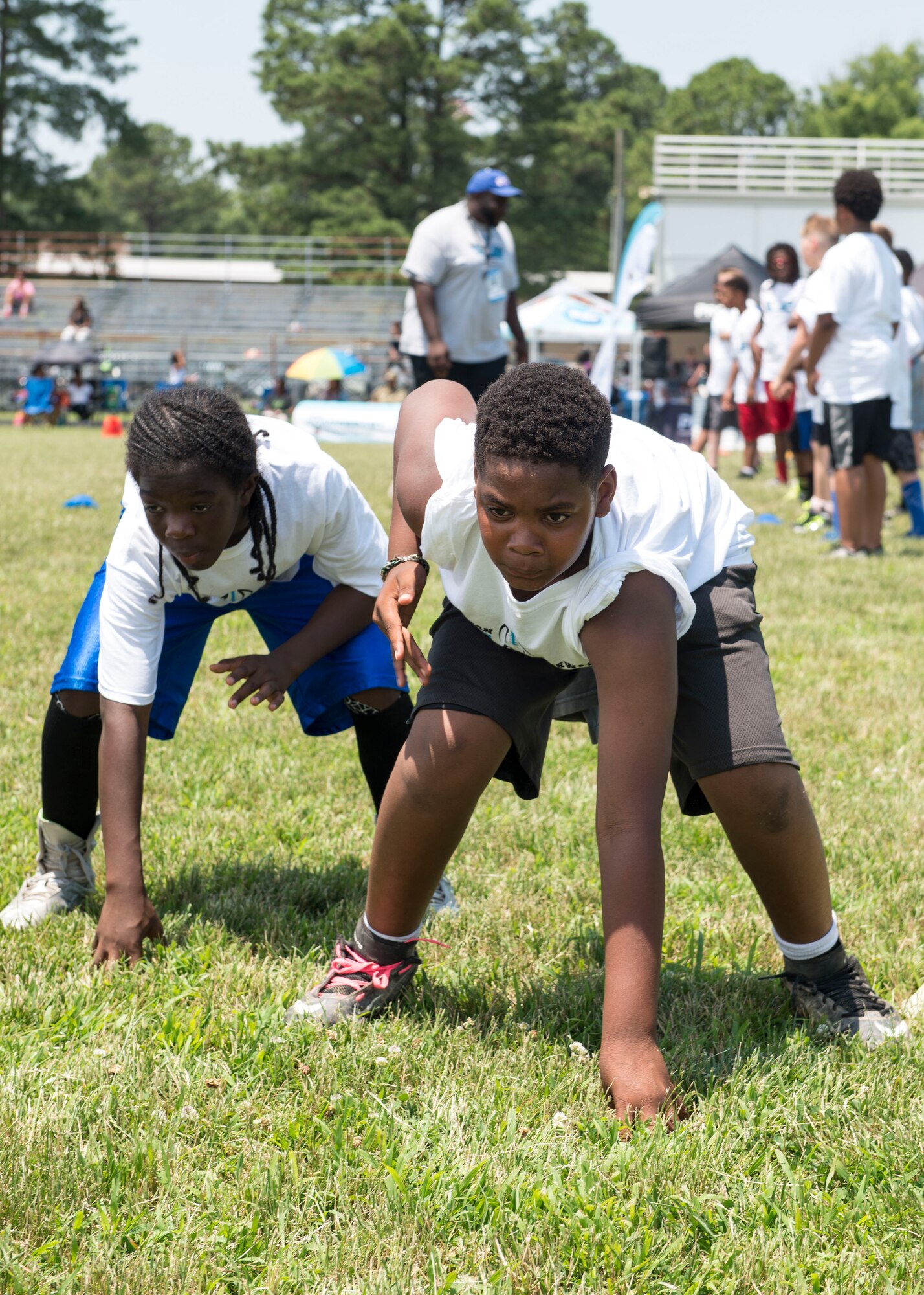 Two participants practice the three-point stance during a football Pro Camp at Fort Eustis, Va., June 21, 2016. The two-day camp provided about 150 children with football drills, teaching them proper stances, route running techniques and how to properly catch a football. (U.S. Air Force photo by Airman 1st Class Derek Seifert)