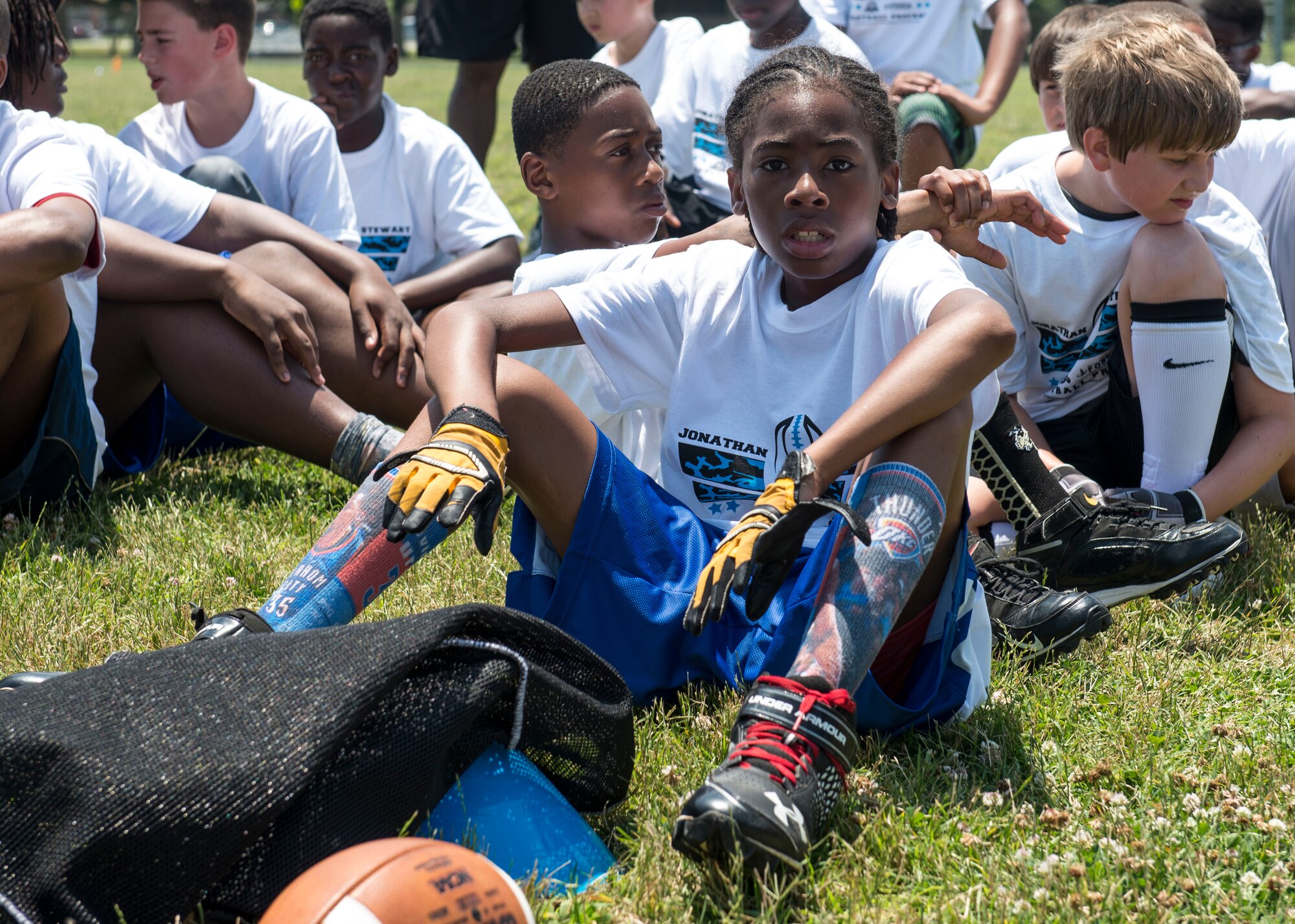 A participant sits with his team during a football Pro Camp at Fort Eustis, Va., June 21, 2016. The two-day event was held for children in grades one through eight who are dependents of active duty, retired or Department of Defense civilian employees. (U.S. Air Force photo by Airman 1st Class Derek Seifert)