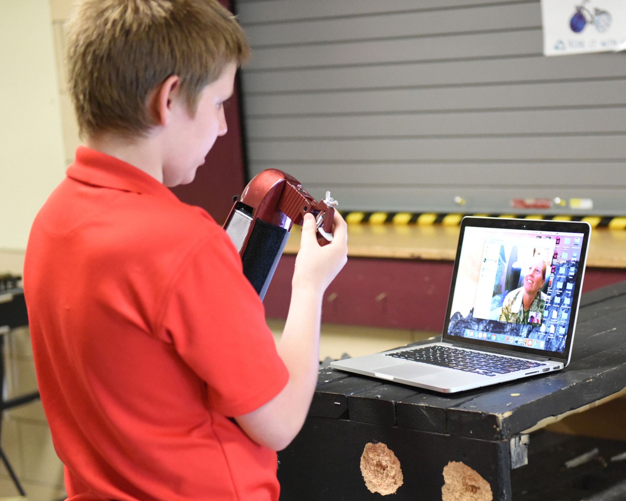 Andrew (A.J.) Mindy shows his mother, Senior Master Sgt. Susan Mindy, a member of Joint Force Headquarters Pennsylvania National Guard, via Skype, his new prosthetic attachment that holds a drum stick, June 7, 2016 at the Pine Grove Area High School, Pine Grove, Penn.  With the ability to hold three attachments, the prosthetic was presented by a high school freshman Nick Brown, the designer of the 3D printed device.  Sgt. Mindy has been deployed for four months.  (U.S. Air National Guard photo by Master Sgt. Matt Schwartz/Released)