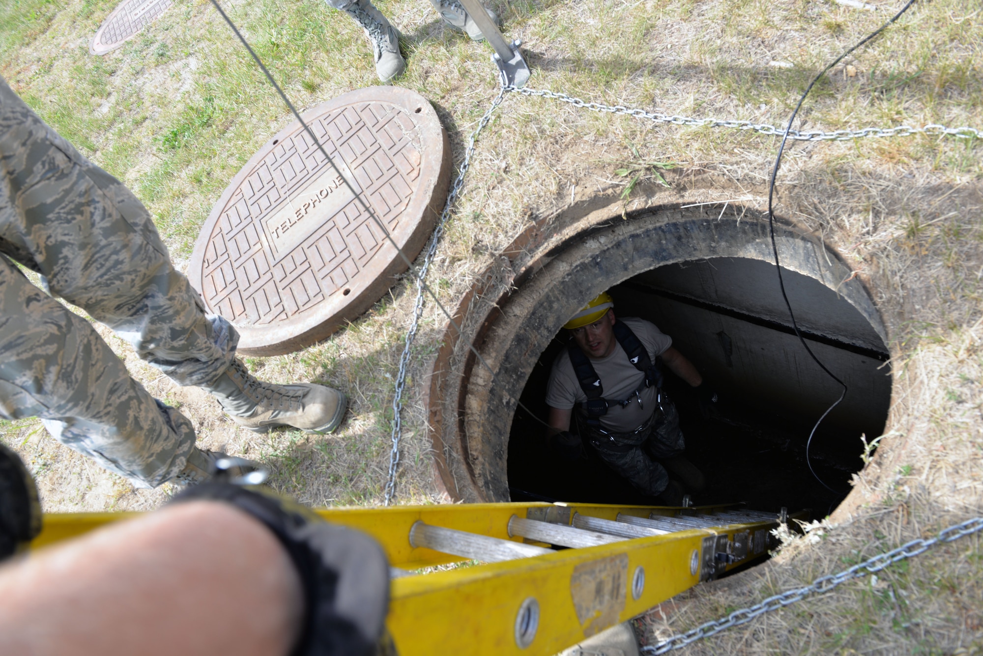 Senior Airmen Mark Chapman, 243rd Engineering Installation Squadron radio frequency transmission technician, speaks to his crew from a manhole at Pease Air National Guard Base, N.H., June 17. The team from Portland, M.E. has assisted the 157th Communications Flight with removing over 20,000 feet of cable from manholes at Pease ANGB. (U.S. Air National Guard photo by Tech. Sgt. Erica Rowe)