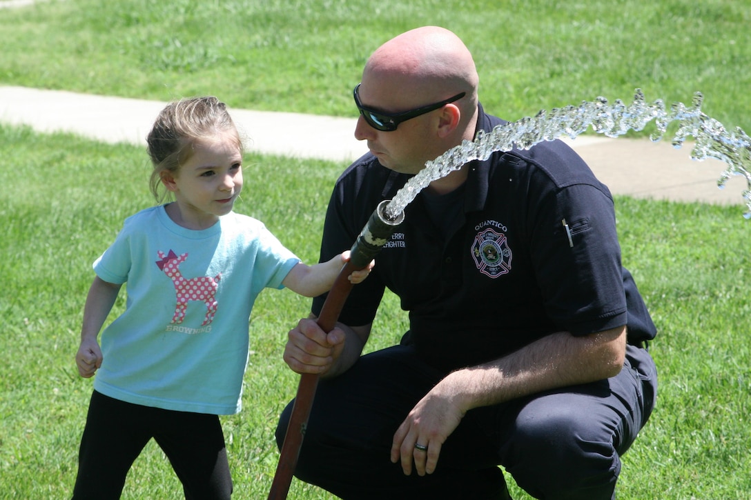 Firefighter Don Perry lets children spray buckets with a fire hose during a sensory-friendly tour of Marine Corps Base Quantico Fire Station 531sponsored recently by the Exceptional Family Member Program.