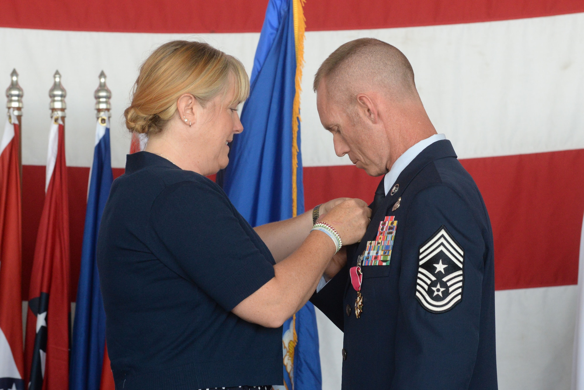 Chief Master Sgt. Geoff Weimer, accepts the retirement pin from his wife, LeAnn, at his retirement ceremony at Minot Air Force Base, N.D., June 24, 2016. Weimer retired after 29 years of service and recently served as the command chief of the 5th Bomb Wing. (U.S. Air Force photo/Airman 1st Class Jessica Weissman)