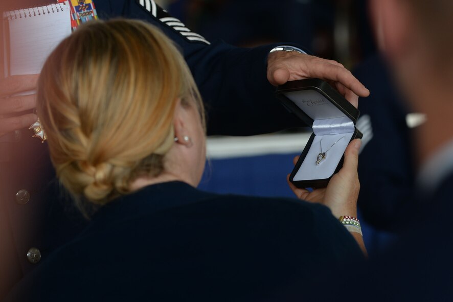 Chief Master Sgt. Geoff Weimer offers a gift to his wife, LeAnn, during his retirement ceremony at Minot Air Force Base, N.D., June 24, 2016. Weimer served as the command chief of the 5th Bomb Wing since July 2014. (U.S. Air Force photo/Airman 1st Class Jessica Weissman)