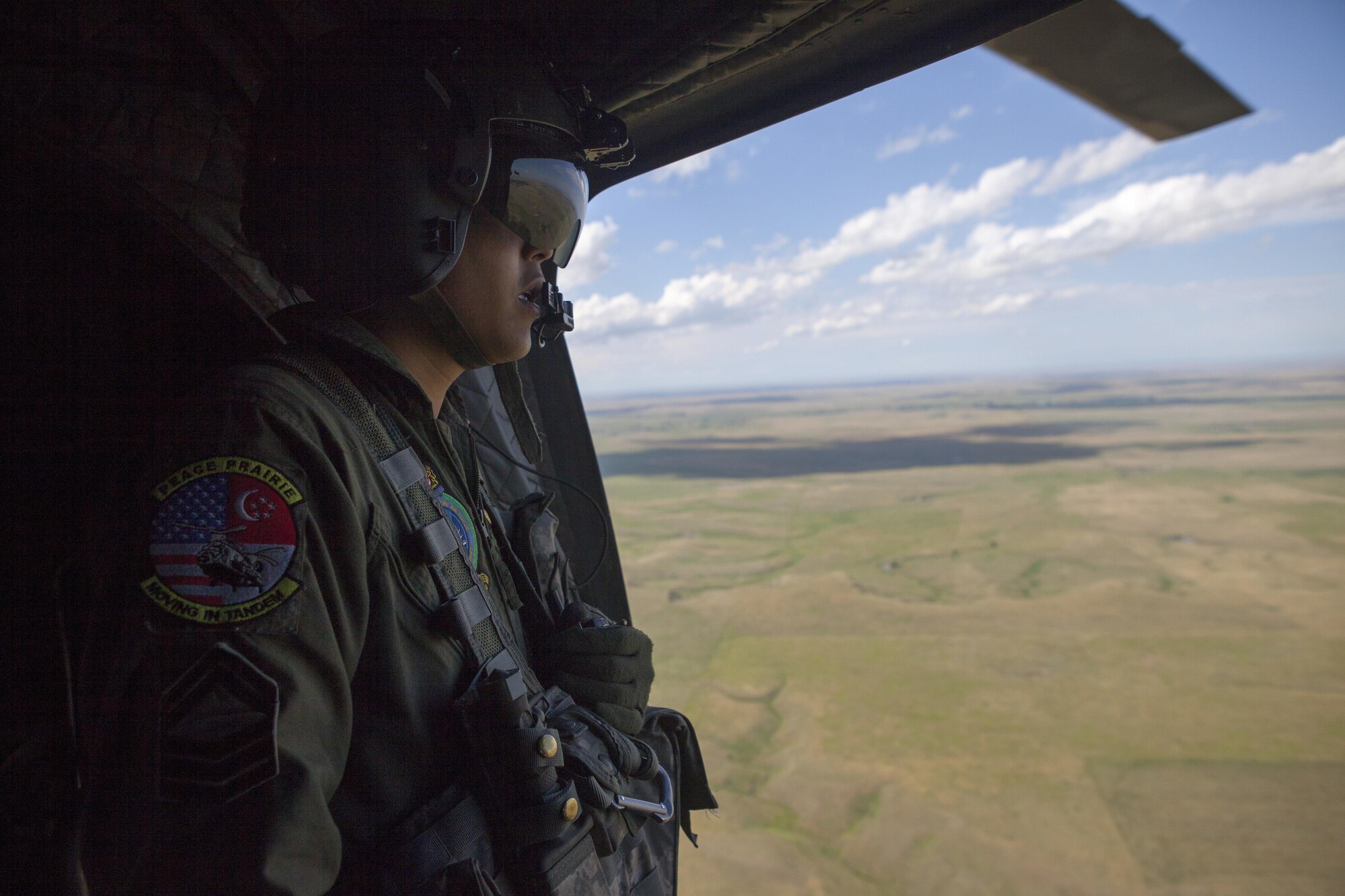 A Republic of Singapore Air Force Airman performs duties as a crewmember on an RSAF CH-47 D Chinook helicopter, while traveling to the Mystic drop zone to perform sling load operations in support of the Golden Coyote training exercise at the South Dakota National Guard West Camp Rapid training facility, Rapid City, S.D., June 14, 2016. The Golden Coyote exercise is a three-phase, scenario-driven exercise conducted in the Black Hills of South Dakota and Wyoming, which enables commanders to focus on mission essential task requirements, warrior tasks and battle drills. (U.S. Army photo by Spc. Kristen Root/Released)