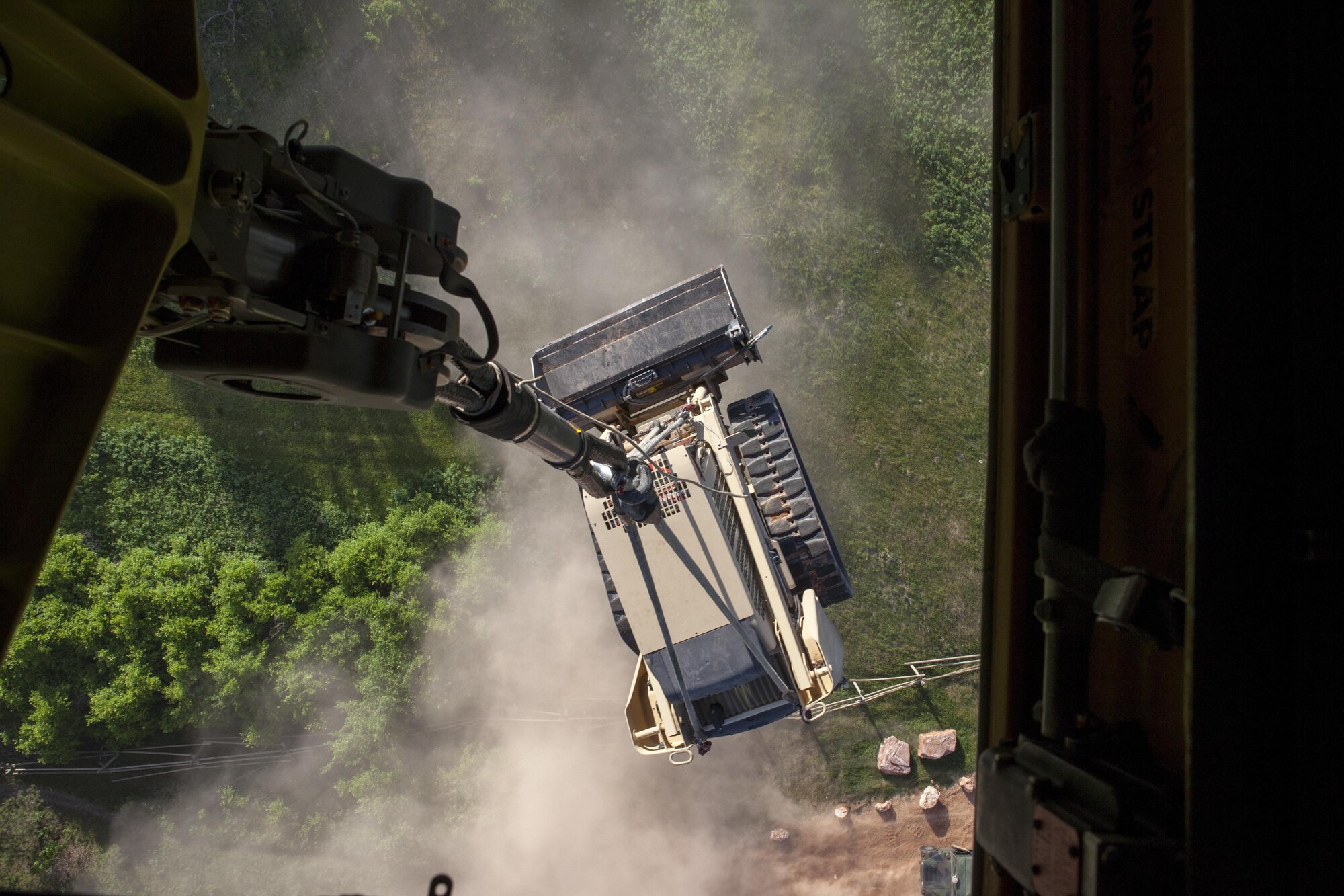 Republic of Singapore Air Force Airmen perform sling load operations at the Mystic drop zone, hoisting a Bobcat S450 skid steer loader with an RSAF CH-47 D Chinook helicopter in support of the Golden Coyote training exercise at the South Dakota National Guard West Camp Rapid training facility, Rapid City, S.D., June 14, 2016. The Golden Coyote exercise is a three-phase, scenario-driven exercise conducted in the Black Hills of South Dakota and Wyoming, which enables commanders to focus on mission essential task requirements, warrior tasks and battle drills. (U.S. Army photo by Spc. Kristen Root/Released)