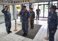 U.S. Navy Lt. Benjamin Sacramento, commanding officer of the Navy Operational Support Center (NOSC) Youngstown, salutes while leading U.S. Air Force Reserve honorary 2nd Lt. Corbin Burggraf, the 910th Airlift Wing’s 63rd Pilot for a Day, in a piping aboard ceremony. Burggraf’s father George watches from the entryway. For Burggraf’s piping aboard, a member of the Navy staff rang a large bell twice, and another member sounded the pipe. The ceremony comes from a Navy tradition of sounding a bell or pipe to announce the boarding of an officer or dignitary. The Pilot for a Day program welcomes children with life threatening or chronic illnesses to Youngstown Air Reserve Station for a day of fun military experiences. (U.S. Air Force photo/Eric White)