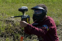 Khai Eshenko, a member of the youth center at Minot Air Force Base, N.D., aims toward his opponent during Paintball 101 June 17, 2016. This program was offered through the summer camps program to teach children the basics of paintball.  (U.S. Air Force photo/Airman 1st Class Jessica Weissman)