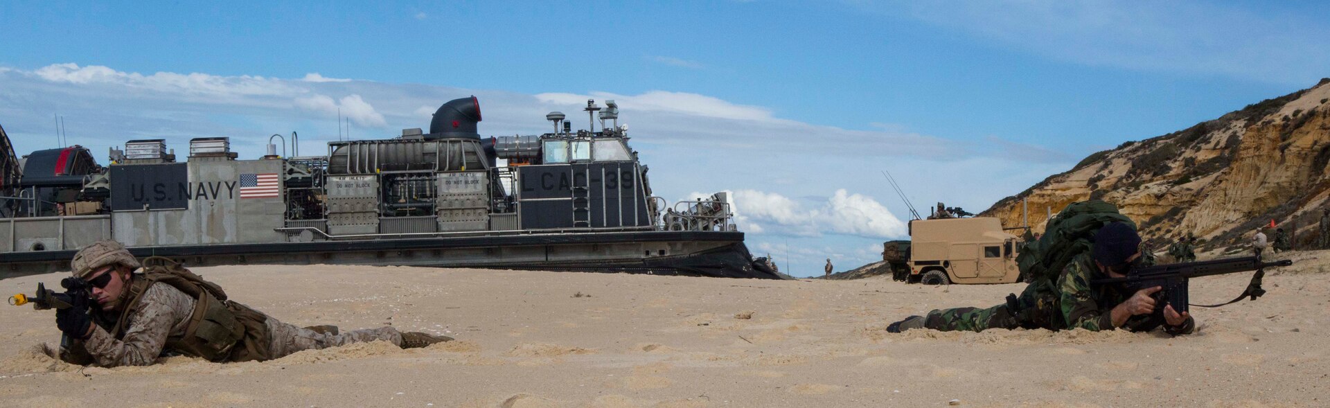 A U.S. Marine with the 26th Marine Expeditionary Unit, from the USS Arlington (LPD-24) holds security with a Portuguese Marine at Pinheiro Da Cruz, Praia Da Raposa beach in Portugal, while participating in a combined amphibious assault exercise, as part of Trident Juncture 2015 Oct. 19. Trident Juncture is a NATO-led exercise designed to certify NATO response forces and develop interoperability among participating NATO and partner nations. (United States Marine Corps photo by Sgt. Austin Long/ Released)