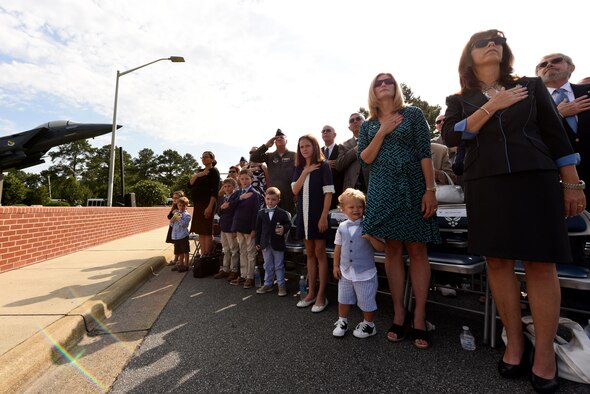Family members and friends of the 4th Fighter Wing change of command official party stand during the National Anthem, June 30, 2016, at Seymour Johnson Air Force Base, North Carolina. Col. Mark Slocum relinquished command to Col. Christopher Sage during the ceremony following a two-year assignment as the 4th FW commander. (U.S. Air Force photo/ Airman 1st Class Ashley Williamson)