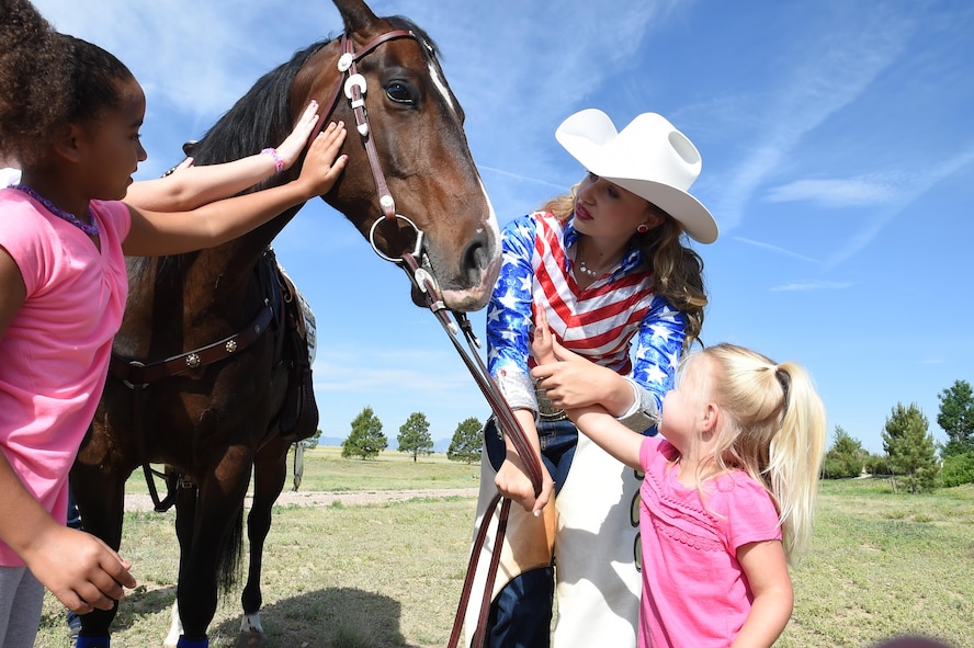 Jamie Tyler Aide to Girl of the West helps Anna Hagberg pet her horse, Jolene outside the Child Development Center at Schriever Air Force Base, Colorado, Friday, June 24, 2016. The Aide to the Girl of the West is one of two young women who represent the West through their horsemanship. They symbolize the youth of our region who wish to further represent the Pikes Peak or Bust Rodeo. (U.S. Air Force Photo/Staff Sgt. Matthew Coleman-Foster)