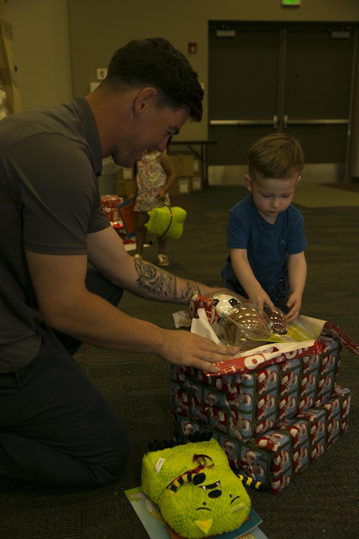 Lance Cpl. Mark Uriarte, team leader, 1st Battalion, 7th Marine Regiment, opens up presents with his son, Kai, at the Armed Services YMCA’s first Christmas You Missed event at building 1707 aboard the Marine Corps Air Ground Combat Center, Twentynine Palms, Calif., June 25, 2016. (Official Marine Corps photo by Lance Cpl. Dave Flores/Released)