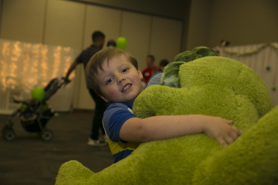 Leo Stainbrook, 3, son of Sgt. Kyle A. Stainbrook, platoon sergeant, 1st Battalion, 7th Marine Regiment, carries the new stuffed dinosaur he received from Santa Claus during the Armed Services YMCA’s first Christmas You Missed event at building 1707 aboard the Marine Corps Air Ground Combat Center Twentynine Palms, Calif., June 25, 2016. (Official Marine Corps photo by Lance Cpl. Dave Flores/Released)