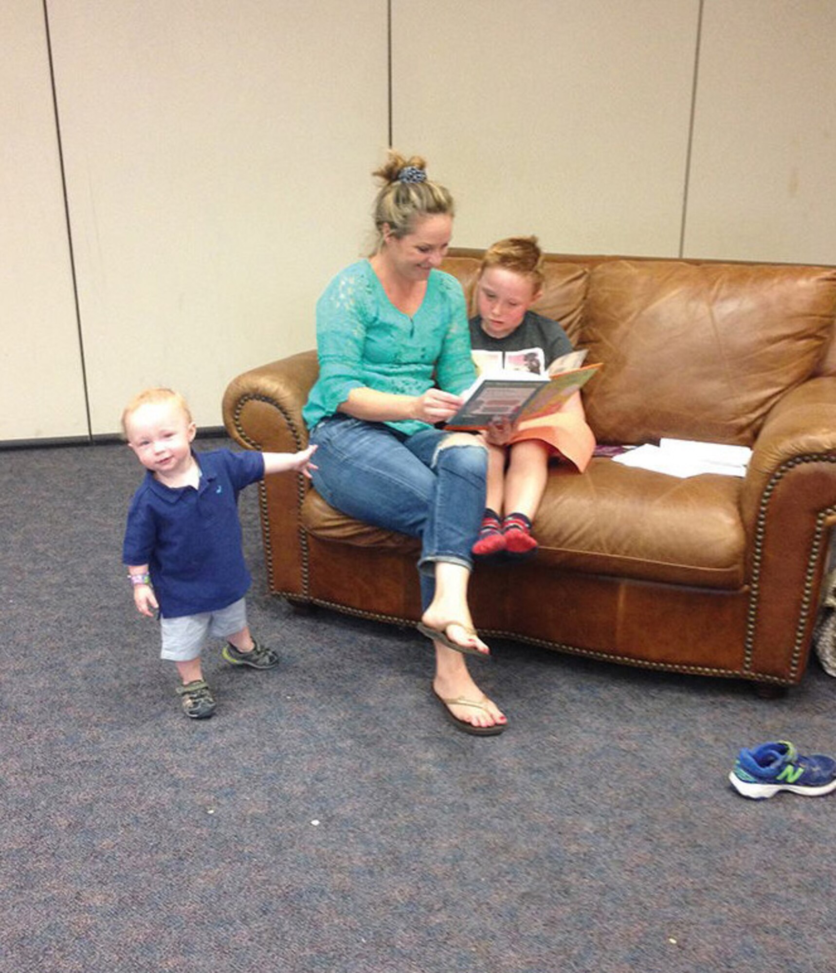 RieAnn Chavez-Gettings and her sons Samuel, 6, and Noah, 1, sit and read during Summer Storytime at the Kirtland Spouses' Club. (Photo by Rebekah Molloy)