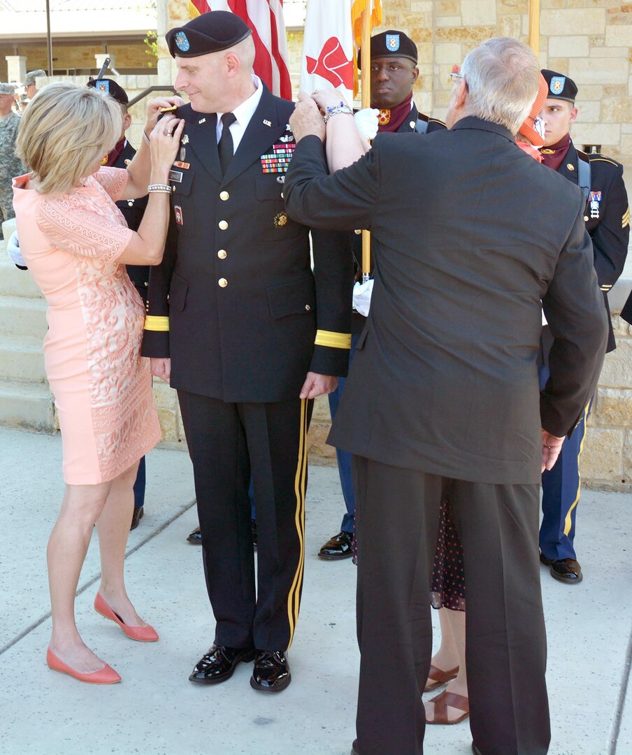 Col. Jeffrey Johnson’s wife, Paula, and his parents, Dorothy and Jack Johnson, place the rank of brigadier general on his uniform jacket June 21 during a promotion ceremony at the Warrior and Family Support Center Amphitheater at Fort Sam Houston.