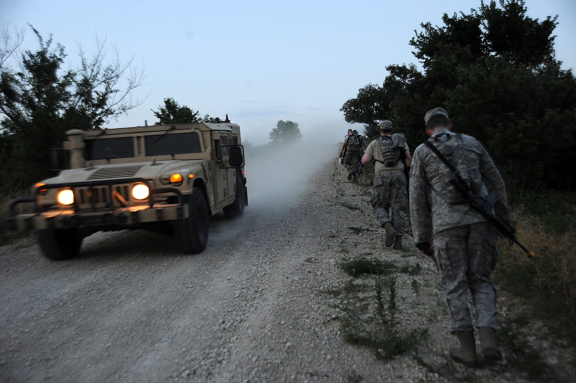 Tenth Air Support Operations Squadron joint terminal attack control Airmen trudge uphill during land navigation operations as a convoy passes, June 22, 2016, at Fort Riley, Kan. Tenth ASOS JTAC Airmen conducted exercises to maintain readiness as tactical air control party operators.  (U.S. Air Force photo/Airman 1st Class Jenna K. Caldwell)