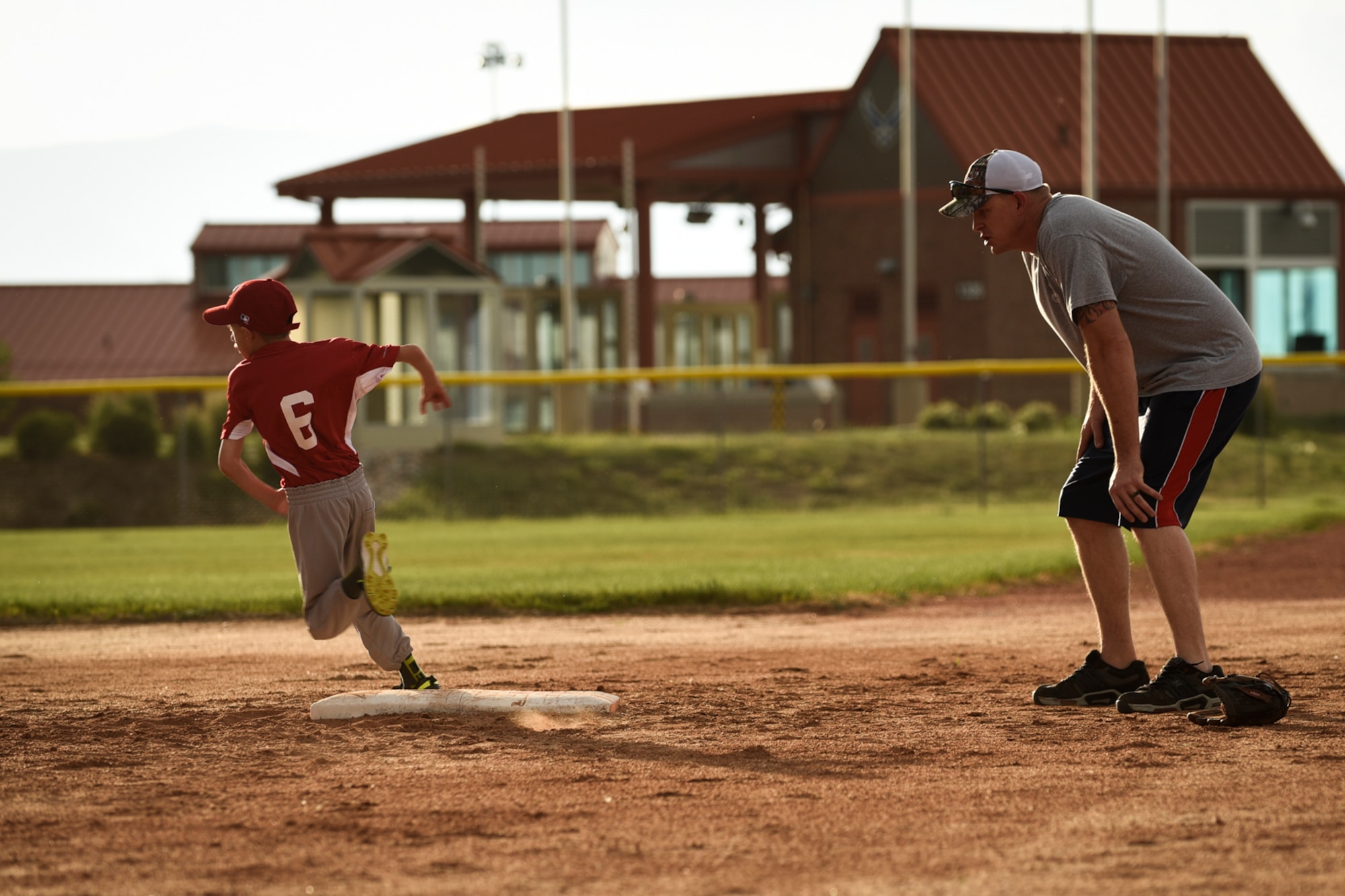 PETERSON AIR FORCE BASE, Colo. – Tech. Sgt. Darin Carson, North American Aerospace Defense Command and U.S. Northern Command and team coach, encourages Owen Doucett as he rounds a base during practice here June 27, 2016. The youth baseball team was practicing the fundamentals to get ready for their first game July 7. (U.S. Air Force photo Senior Airman Rose Gudex)