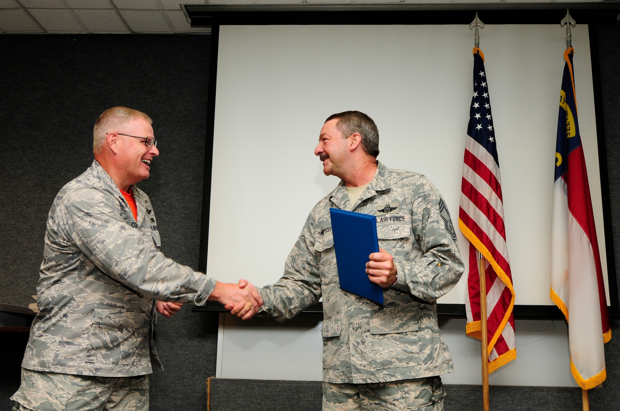 U.S. Air Force Col. Marshall C. Collins (left), commander, 145th Airlift Wing, shakes hands with Chief Master Sgt. Andrew Huneycutt (right), 145th Operations Support Squadron (OSS) chief loadmaster, after presenting him with the 12,500 Mishap-Free Flying Hour Milestone Award during a ceremony held at the North Carolina Air National Guard Base, Charlotte Douglas International Airport, June 4, 2016. Huneycutt provides leadership and management of the 156th Airlift Squadron and 145th OSS flying and ground training programs which ensures operational readiness of its members. (U.S. Air National Guard photo by Staff Sgt. Julianne M. Showalter/Released)