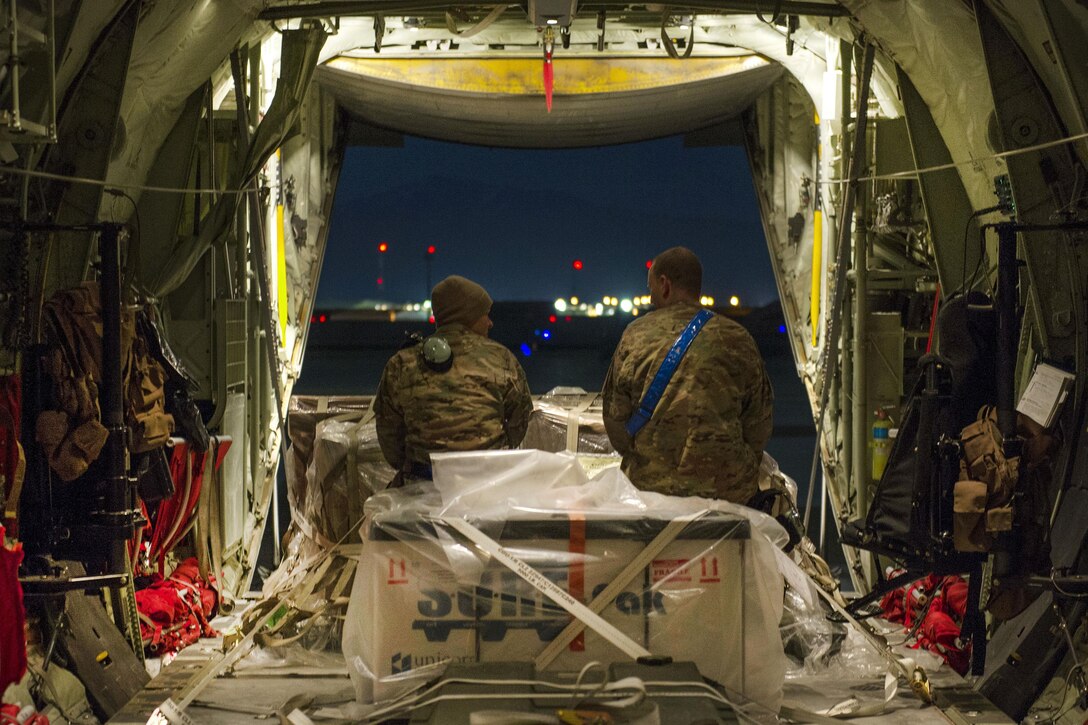 Air Force Senior Airman Alec Flores and Air Force Staff Sgt. Eric Mingues talk in the back of a C-130J Super Hercules aircraft before a night sortie on Bagram Airfield, Afghanistan, Feb. 22, 2016. Flores and Mingues are crew chiefs assigned to the 455th Expeditionary Aircraft Maintenance Squadron. The squadron ensures that aircraft on Bagram are prepared for flight and return them to a mission-ready status once they land. Air Force photo by Tech. Sgt. Robert Cloys
