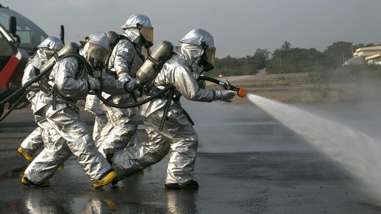 A group of Marines simulate spraying fuel away from them as they move closer to an engulfed aircraft during a training event as part of Exercise Cobra Gold 16 at Utapao, Thailand, Feb. 19, 2016. Marines and Royal Thai sailors worked together throughout the exercise to build bonds and skills. Cobra Gold is a multi-national exercise designed to increase interoperability and relations between participating nations in the Asia-Pacific region. The Marines are with Marine Wing Support Squadron 172, Marine Aircraft Group 36, 1st Marine Aircraft Wing, III Marine Expeditionary Force.