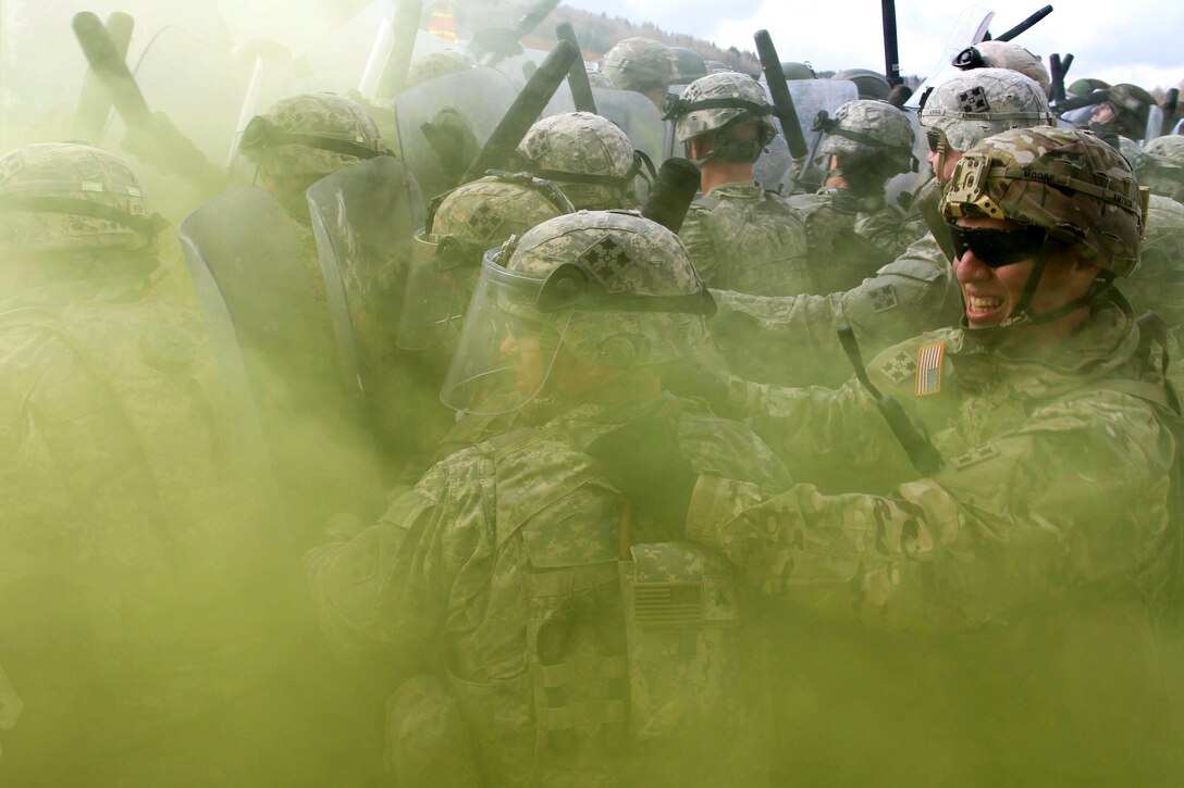 U.S. soldiers engage mock protesters through a yellow haze during crowd control training at the Joint Multinational Readiness Center in Hohenfels, Germany, Feb. 25, 2016. Army photo by Staff Sgt. Thomas Duval